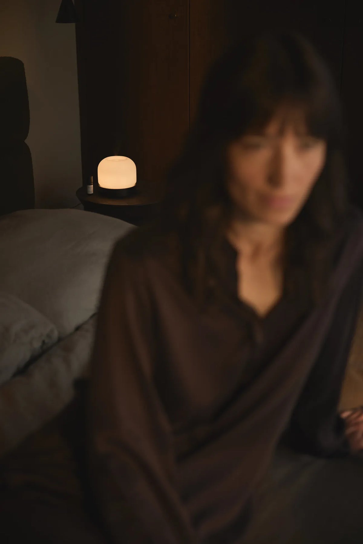A woman in the bedroom, with the Quint Aroma Diffuser from Looops