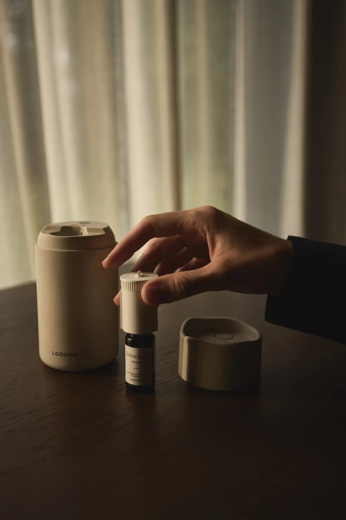 Looops 's Aeris Aroma Diffuser on the desk, hand on the device