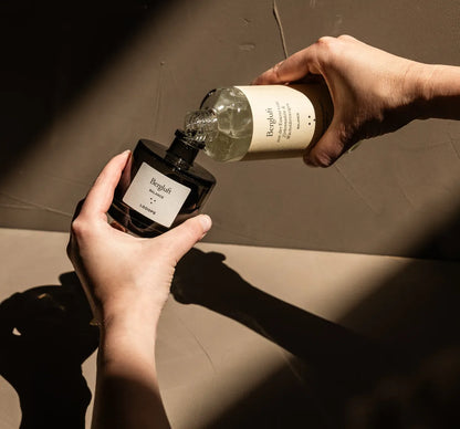 Person fills liquid from a glass bottle into a glass bottle