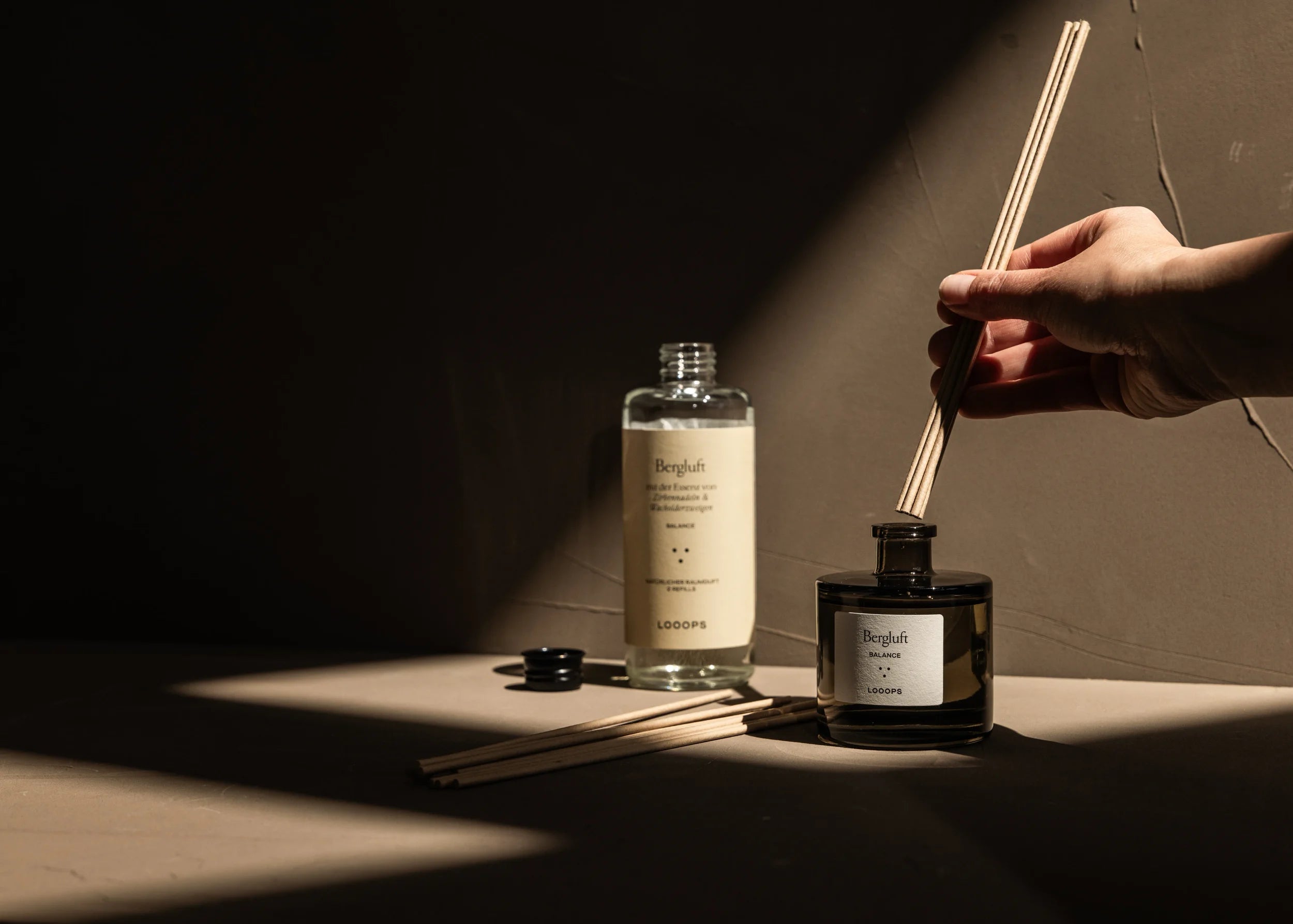 Hand holding paper sticks in a jar of scented sticks