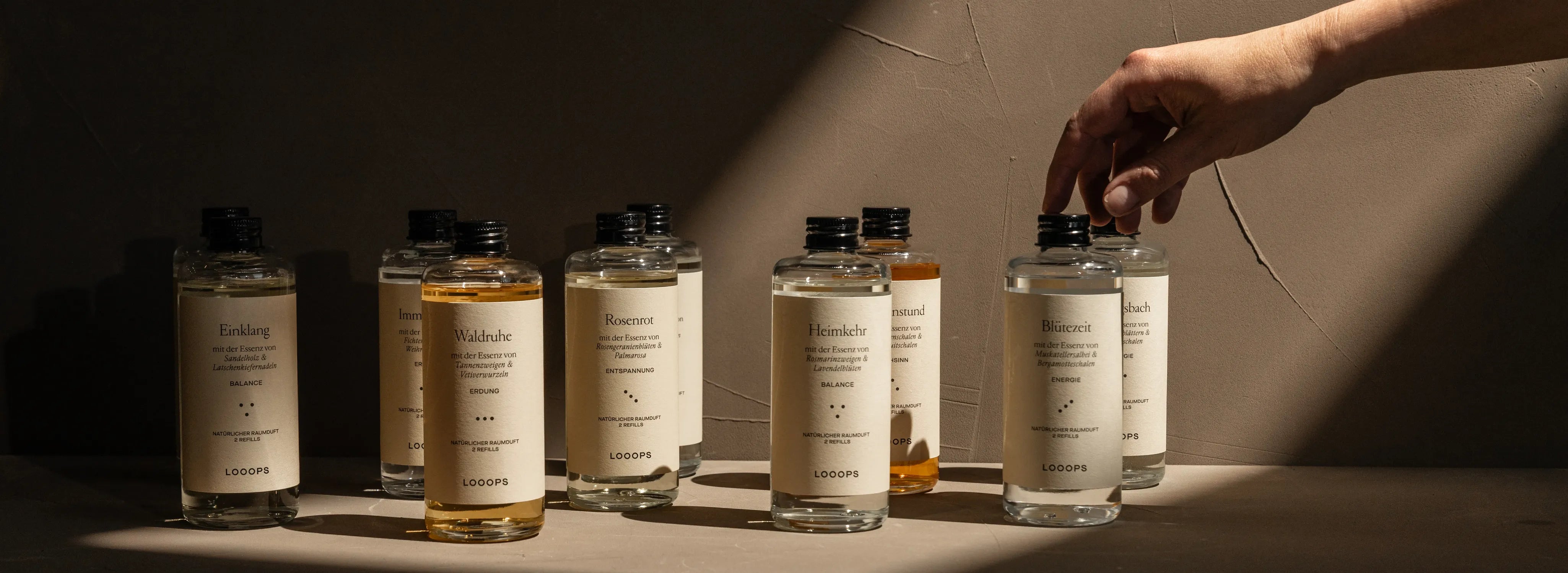 Several glass bottles stand next to each other and Hand reaches for one of them