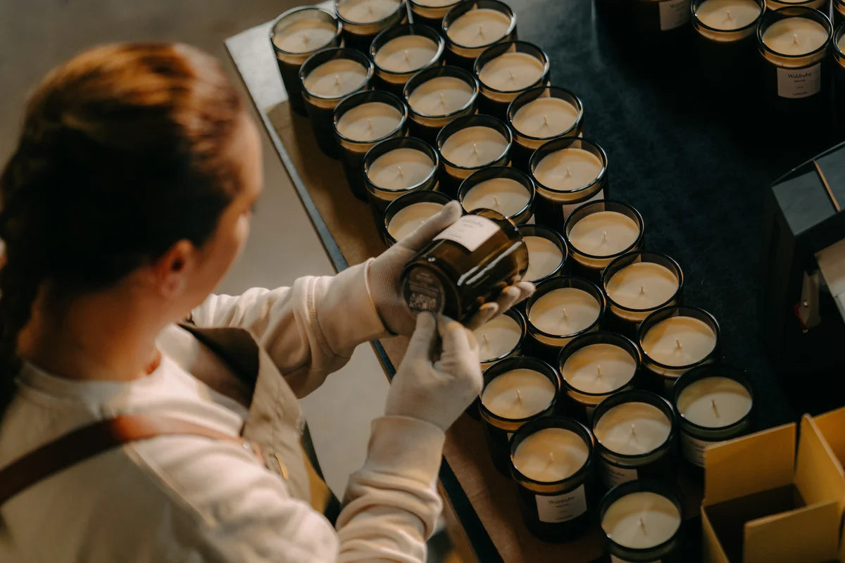 A lady sticks the bottom labels on the filled candles