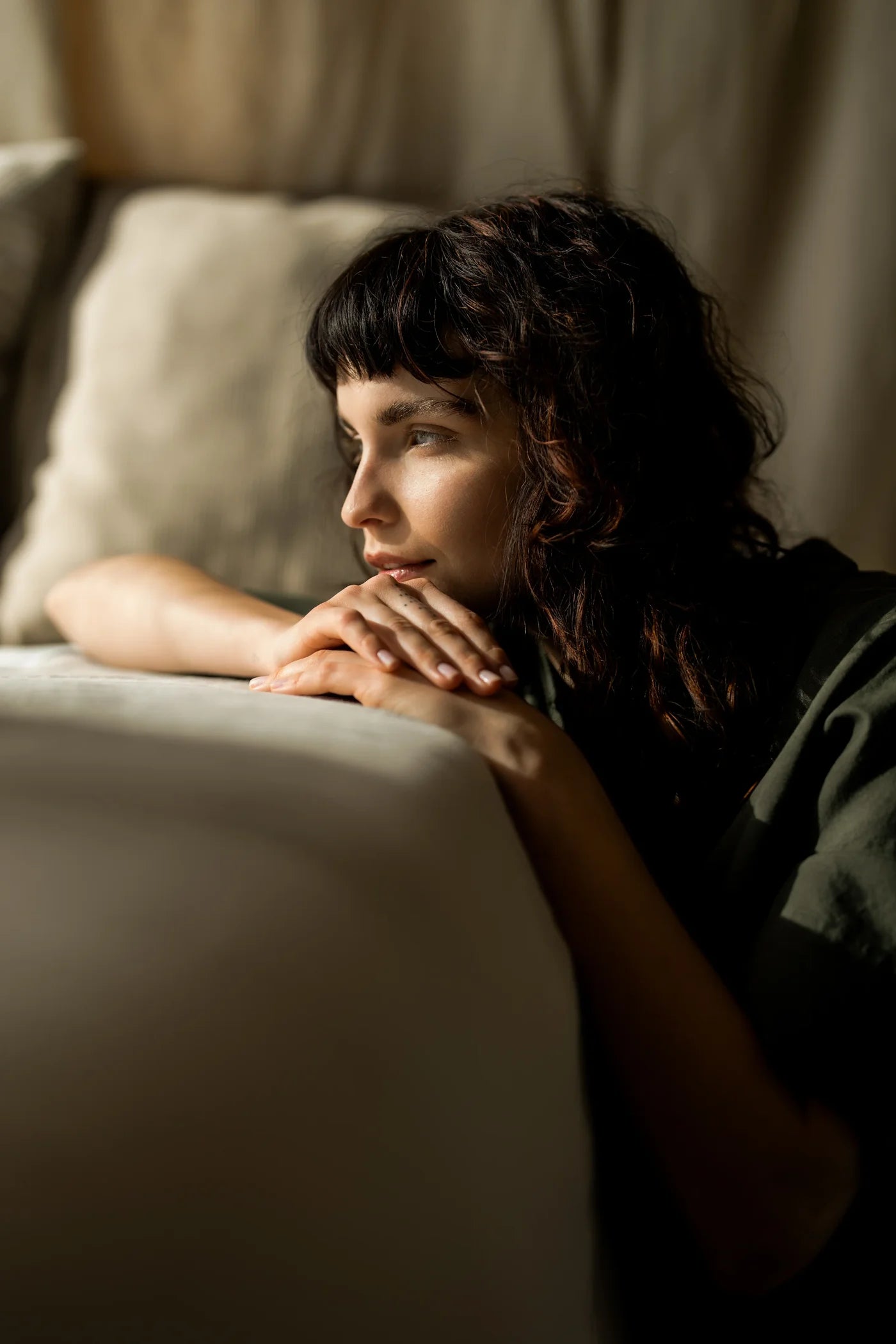 A woman sits on the floor and leans against the sofa.