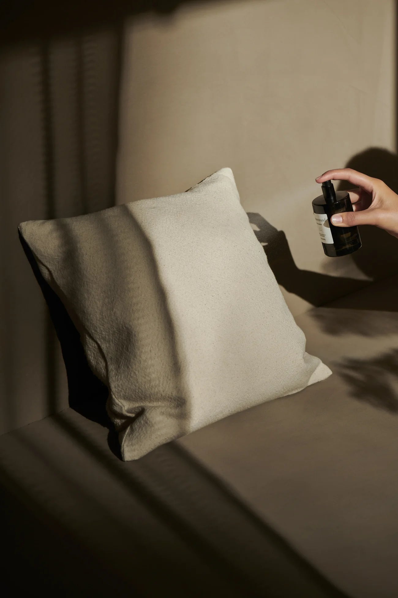 A room spray is sprayed onto a cushion. 