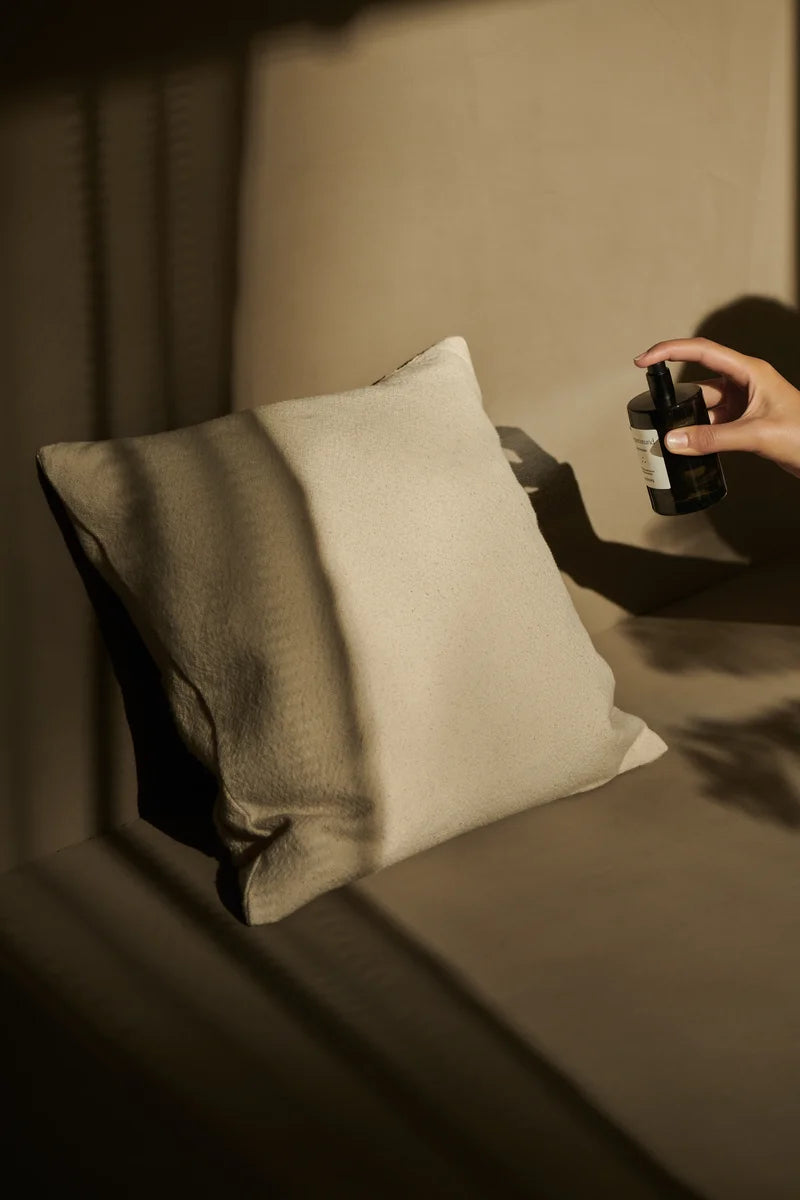 A room spray is sprayed onto a cushion.