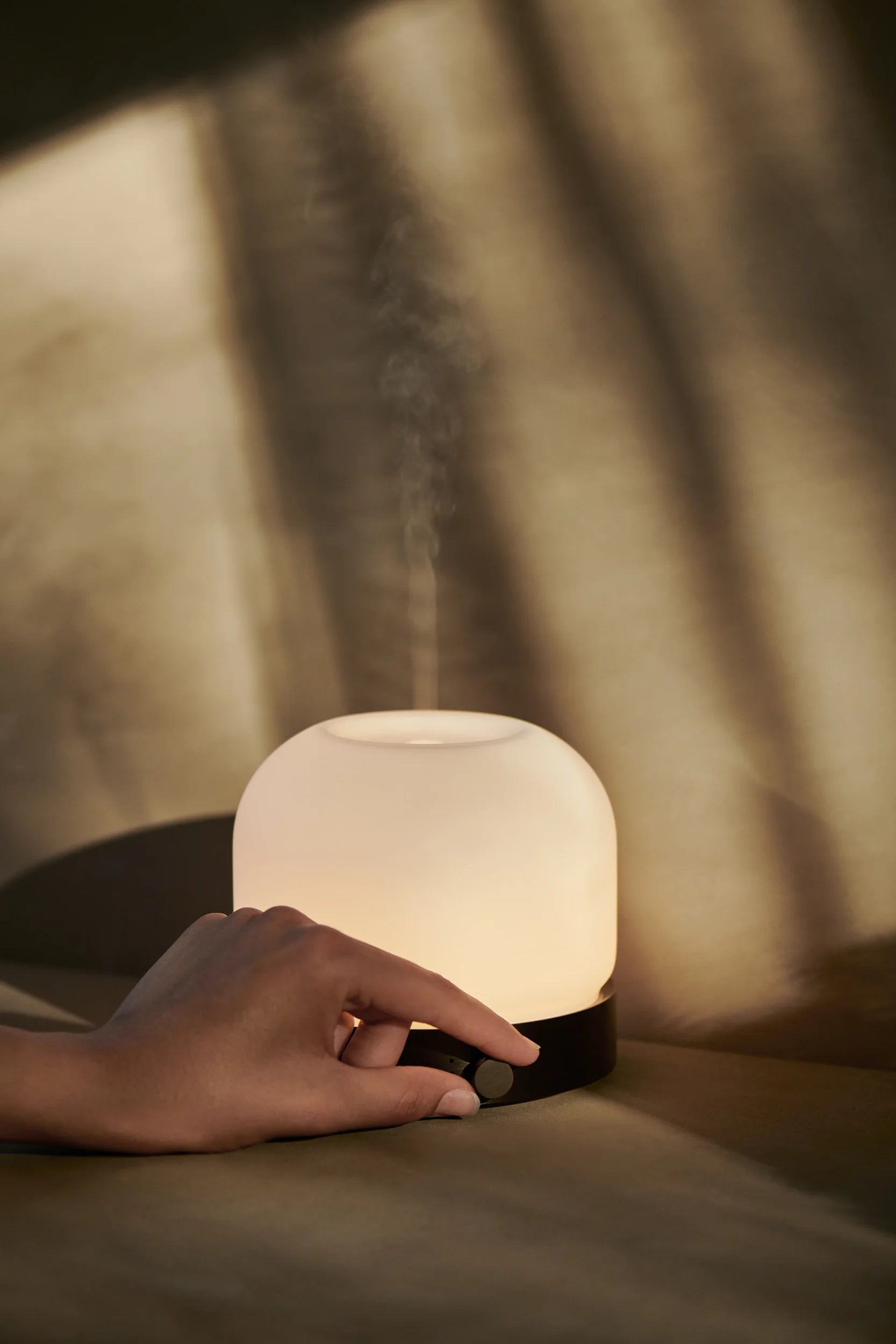 Ein Aroma Diffuser wird von einer Hand eingeschalten. 